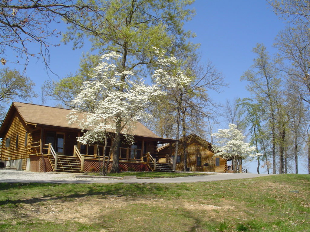 The Dogwood Trees are blooming in front of these rustic log cabins located at Crown Point Resort in Horseshoe Bend, Arkansas